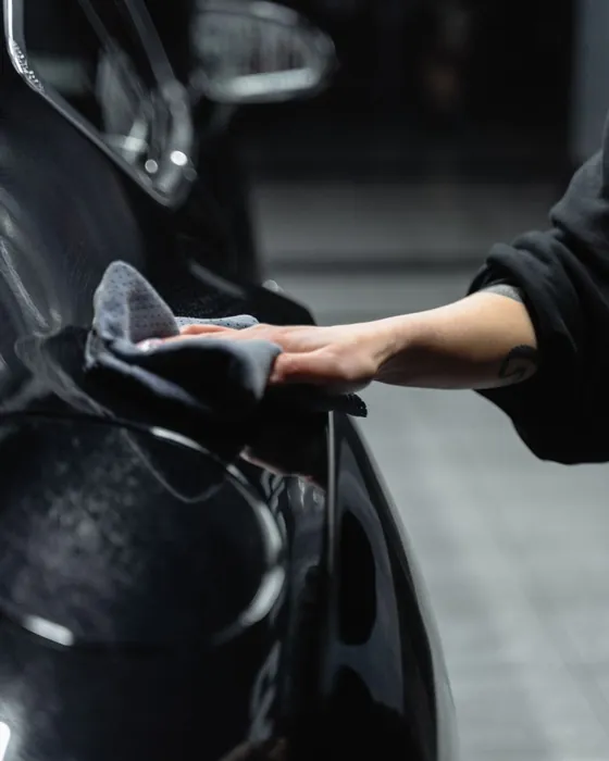 A hand polishing the black bodywork of a car